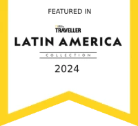 The image features a badge with text: "Featured in National Geographic Traveller Latin America Collection 2024," outlined in yellow with a ribbon shape.